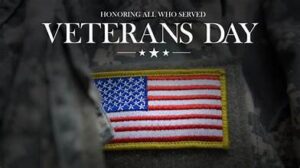 American flag waving at sunrise beside military memorial on Veterans Day 2025 — symbol of honor and gratitude to U.S. veterans.