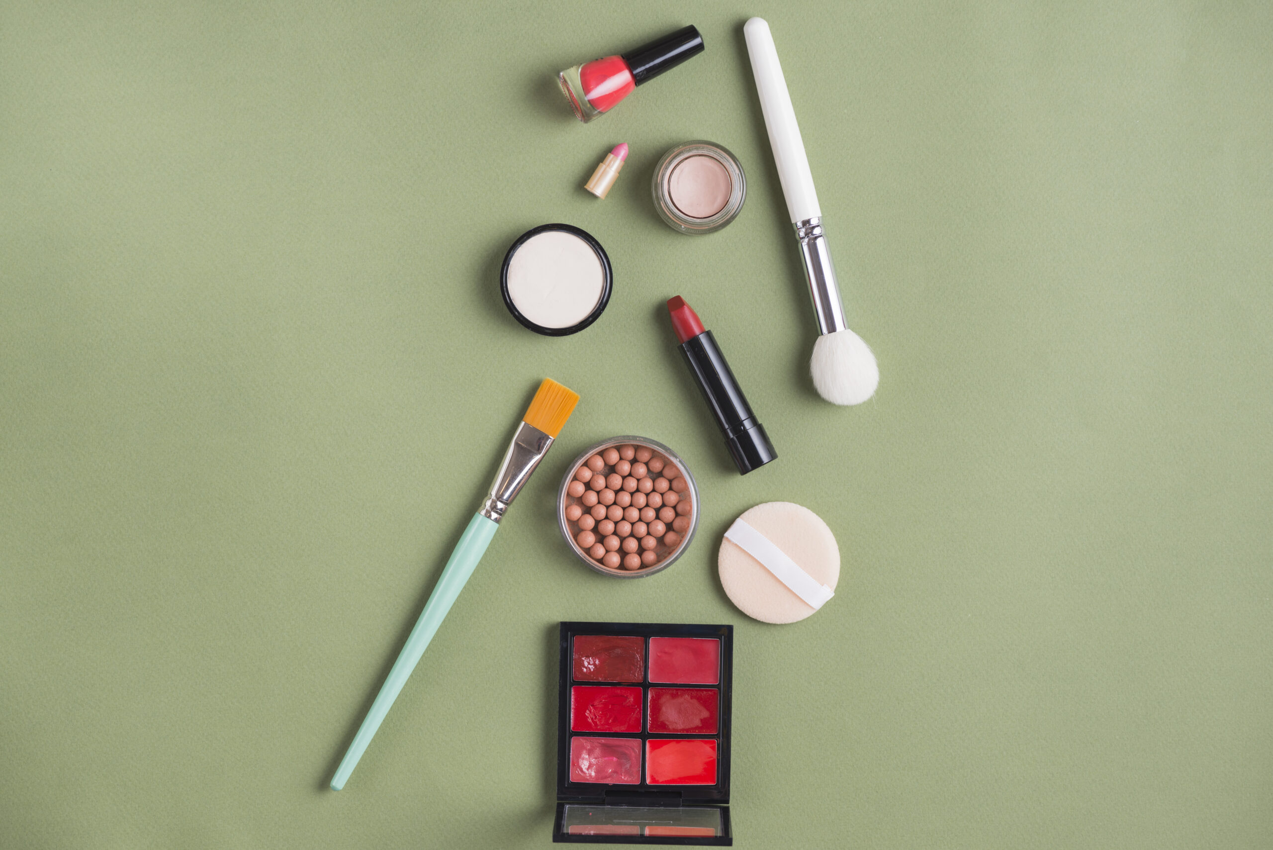 Flat lay of 2025 trending cosmetics products — tubing mascara, powder blush, peptide lip tint, hybrid sticks, and eco-friendly beauty tools displayed on a white vanity surface