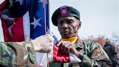 “American soldier standing before the U.S. flag during Veterans Day 2025, representing patriotism, service, and the enduring importance of honoring veterans.”